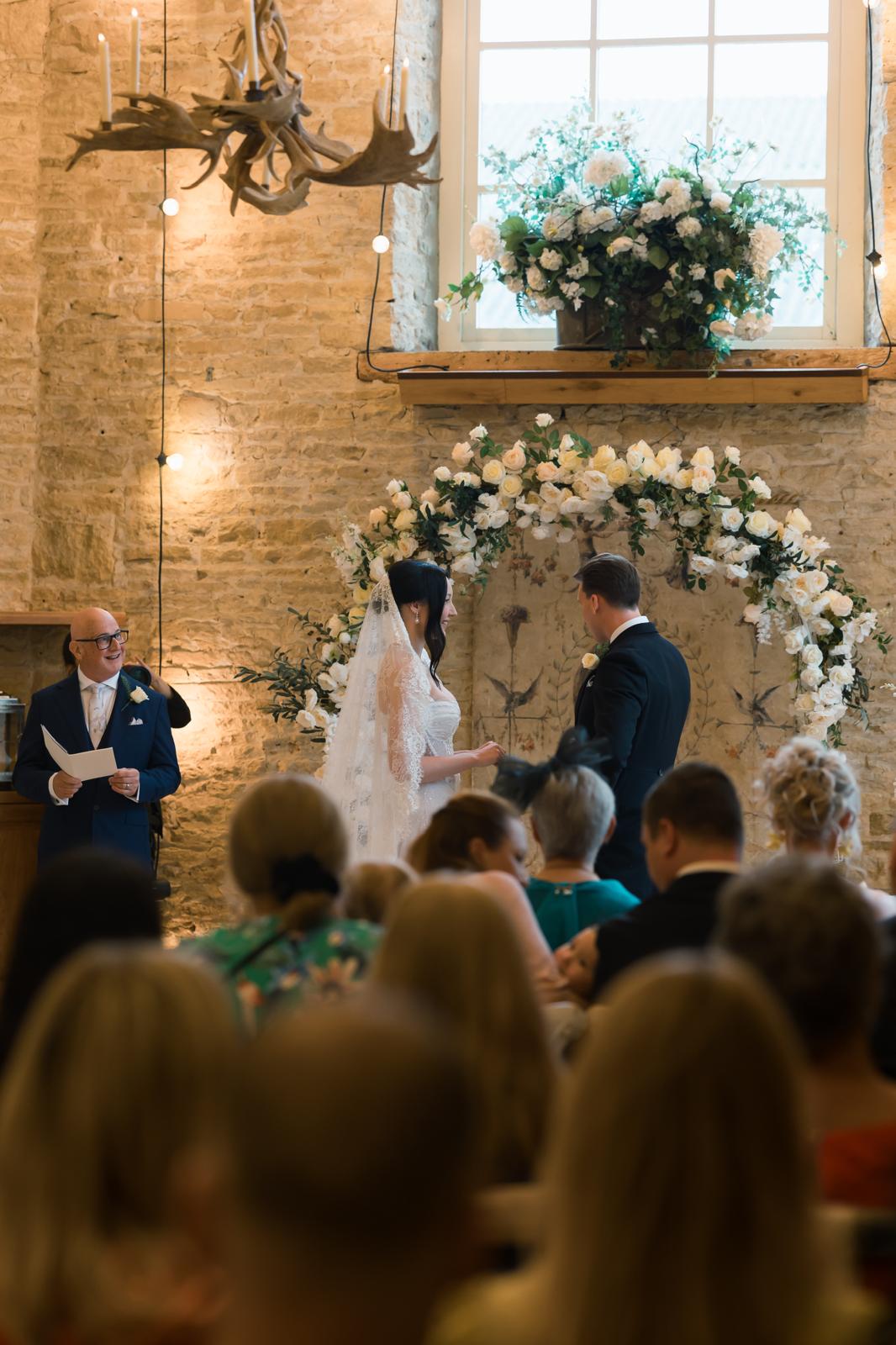 Stephen officiating David and Johanna's wedding in a flower-filled barn